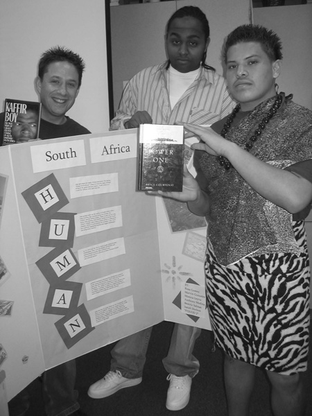 A photo of students holding poster board and books