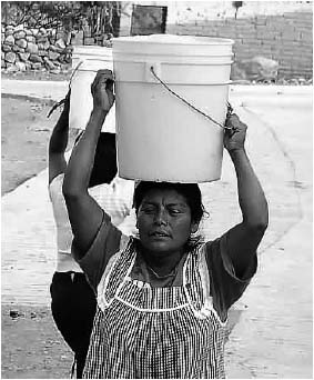 Figure 1 is a photograph of a Woman carrying a bucket of water on her head.