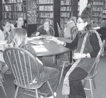 A picture of Kerry Madden talking to a few kids at a library