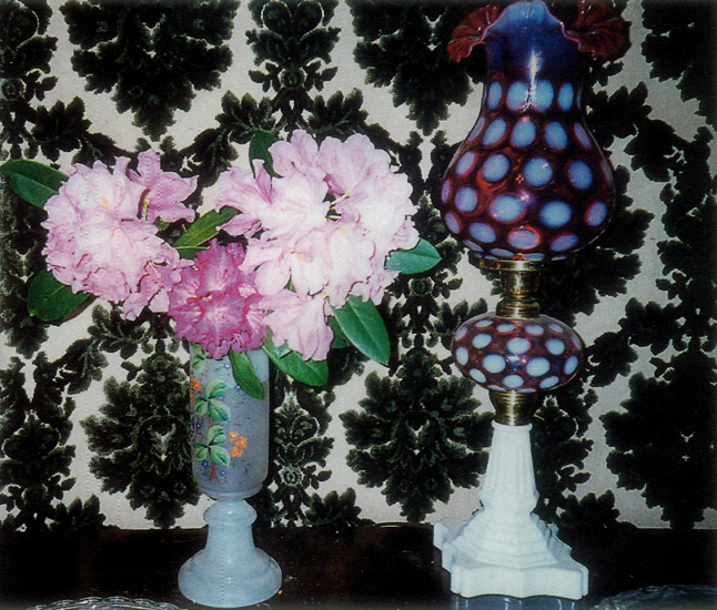 Arrangement using rhododendron trusses, a vase, 
lamp and tapestry