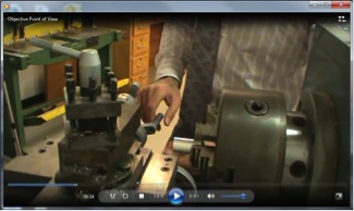 This image is a screenshot of video showing how to assemble a lathe. The view of the instructor is face-on,  across the lathe.
